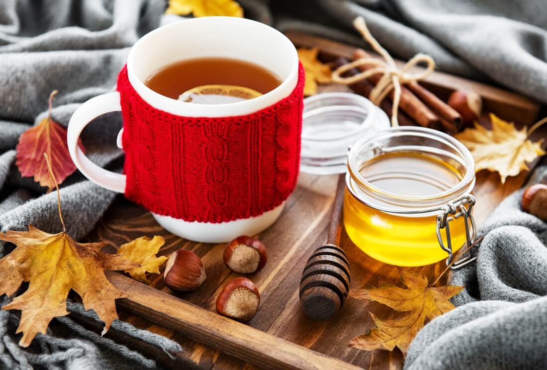 cup of tea and fallen dry yellow leaves on a wooden background