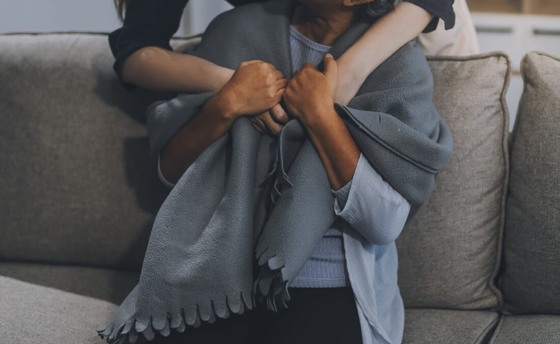 happy family Granddaughter takes care of her grandmother with warm cloths sitting on the sofa.